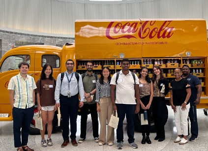 Students stand in front of a yellow 1949 Coca-Cola delivery truck.