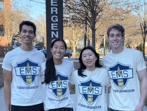 Four students stand in front of emergency sign.