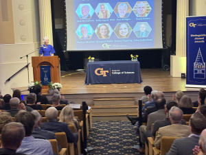 Dean Susan Lozier closed the event by thanking all in attendance for helping to "build a tradition that will continue to highlight the incredible reach of our College of Sciences alumni." a woman at a podium in front of a screen highlighting all of the Distinguished Alumni Award winners.